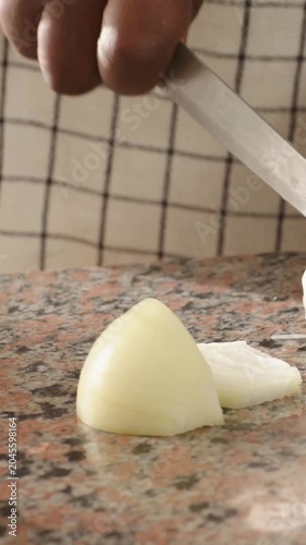 Vertical video: Slicing cook's hand lifting knife to onion in kitchen, prepping slices, copy space
