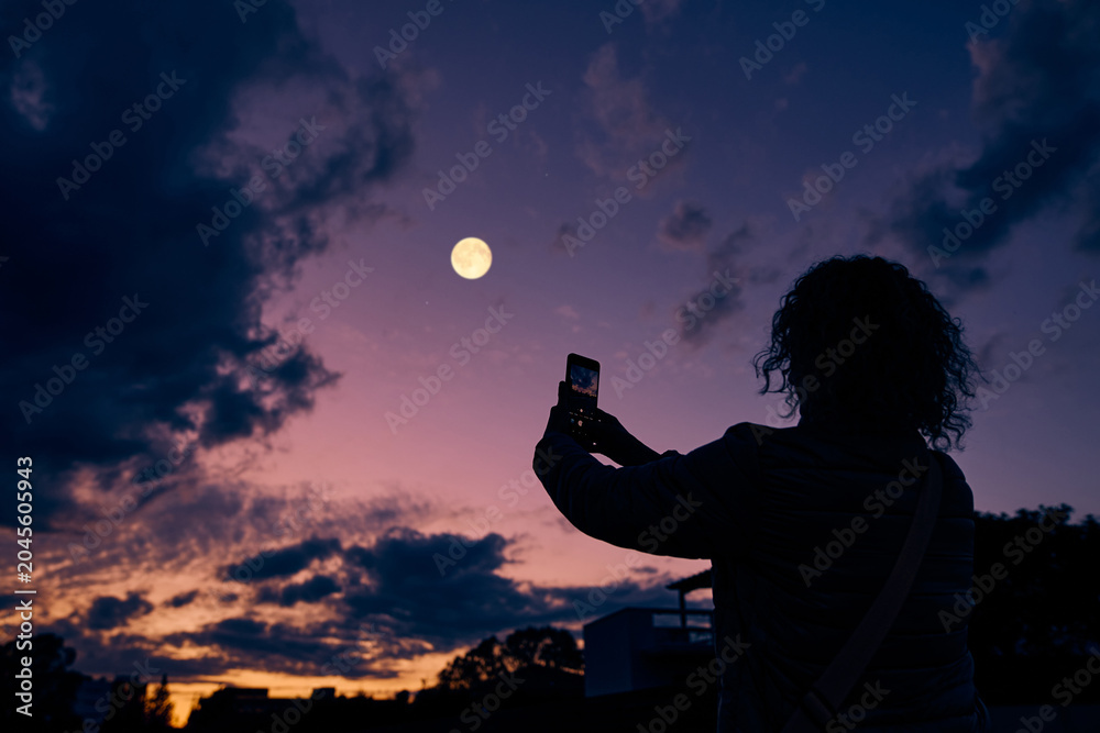 Obraz premium Amateur astronomer with smartphone photographing and observing stars, planets, Moon and other celestial objects.