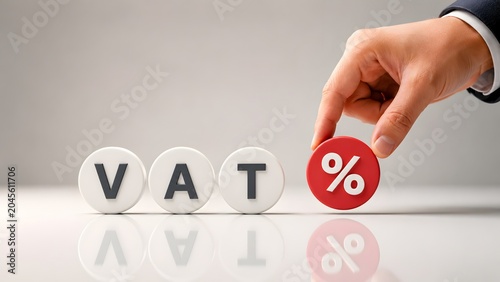 Human hand placing a red percentage symbol next to VAT text blocks representing value added tax financial accounting and business economy