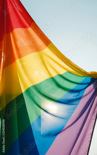 Vibrant rainbow flag waving in the wind with colorful stripes and sunlight shining through fabric