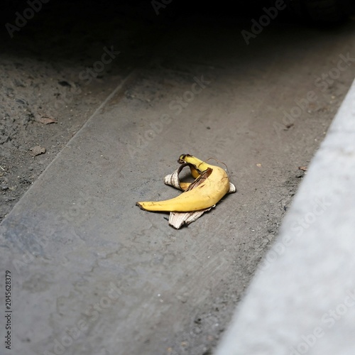 Foto Conceptual banana peel lying on a gritty street curb, perfect for metaphoric commercial advertising and editorial storytelling