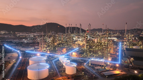 Tableau sur toile Glowing blue digital network lines flowing through a massive oil refinery and petrochemical plant at twilight