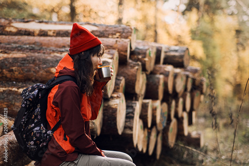 Schilderij op canvas Woman sits on logs in forest drinking from cup