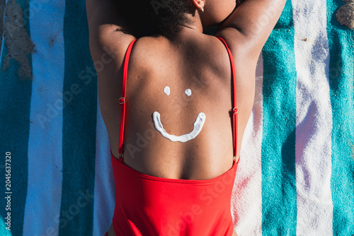 Konstfotografi Person relaxing on beach with sunscreen smiley face