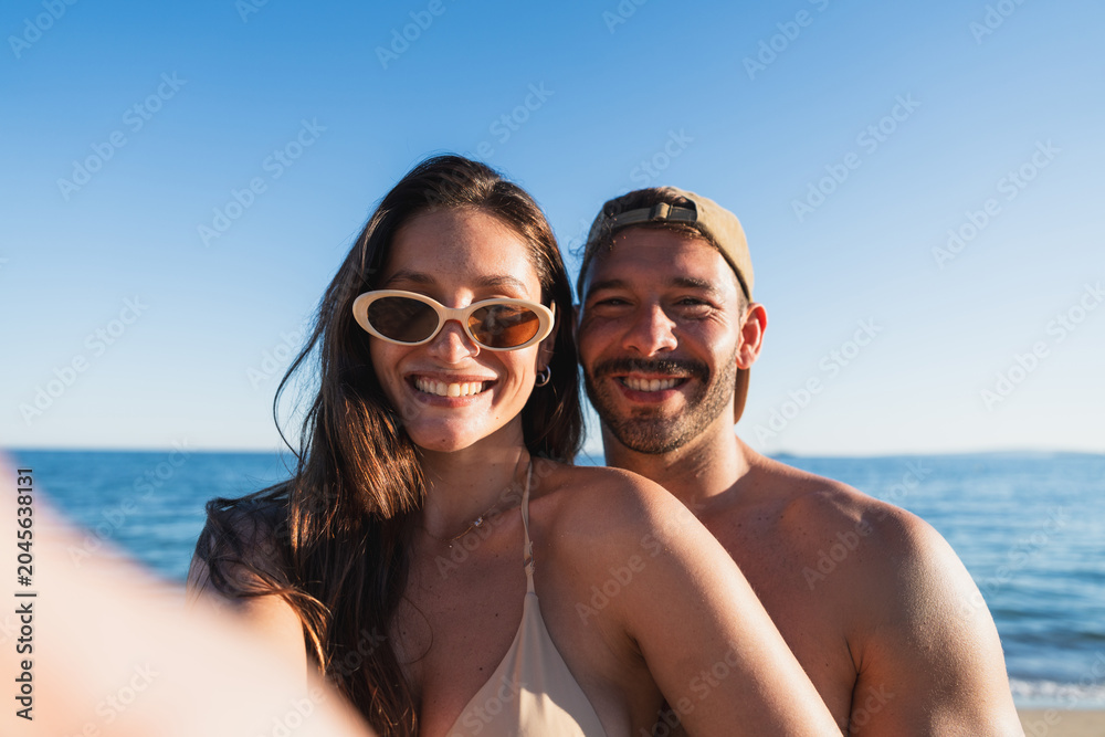 Obraz premium Young couple smiling at camera enjoying summer vacation