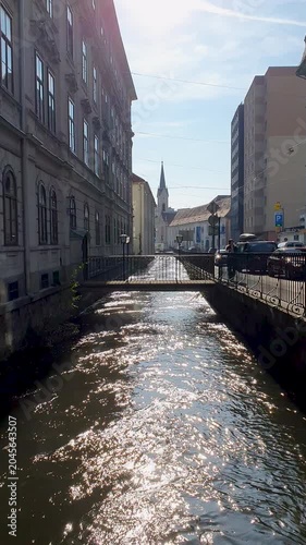 Sunny Canal Street Scene With Bridge, Historic Buildings, and Church Spire in Quiet European City
