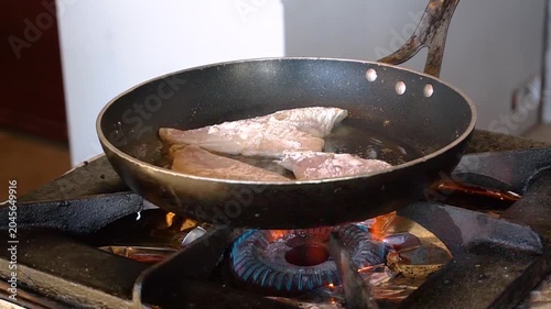 Chef frying fish in a pan in restaurant kitchen