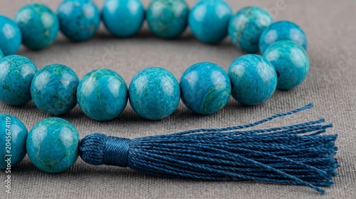 Turquoise beaded bracelet with tassel on neutral textured fabric background