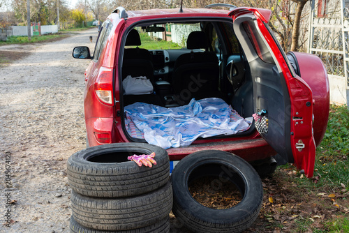 Foto A red car sits along a gravel road as summer tires are removed and replaced with winter tires