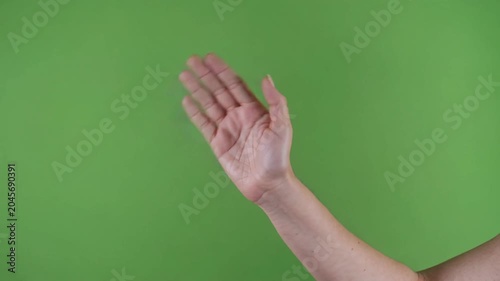 Woman's arm waving her hand to say hello or goodbye. Friendly greeting gesture isolated on a green screen for easy chroma keying