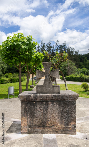 Ancient stone cross monument surrounded by trees in Asturias