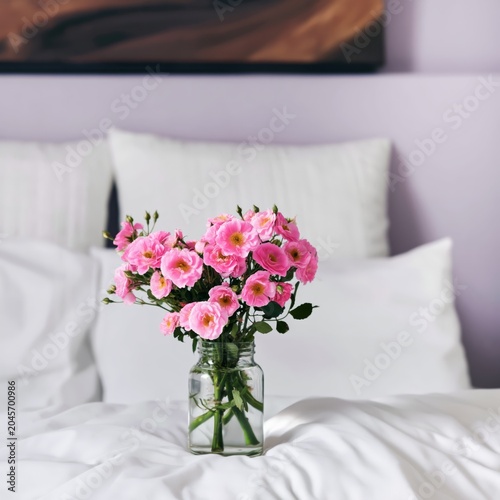 Fresh Flowers on a Bed in a Bright Bedroom With Lamps and Soft Bedding in the...