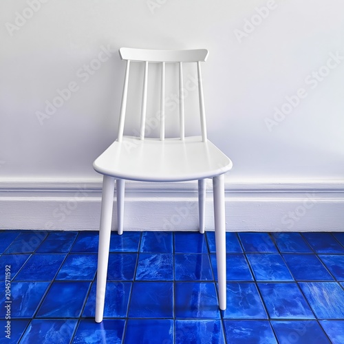 White Chair on Blue Tiled Floor Against Simple Background in Bright Light