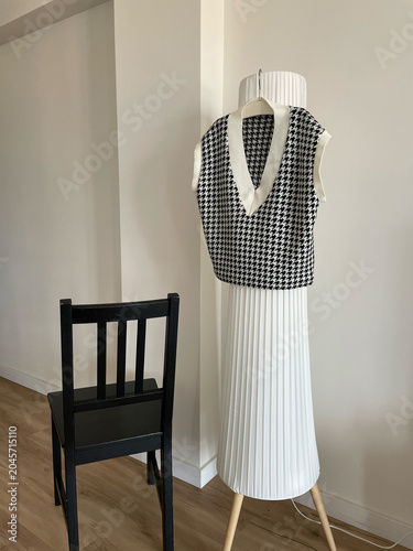 Fashion display features a sleeveless top on a mannequin with a black chair in a modern room during daylight