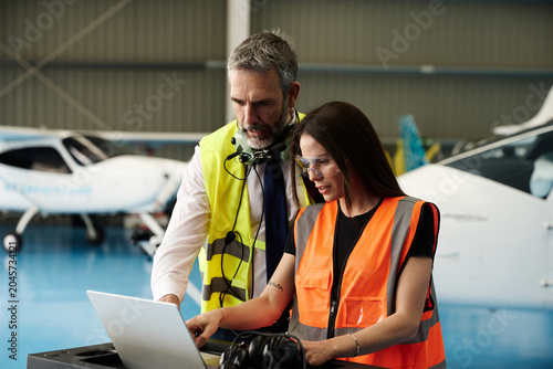 Photography Aviation engineers collaborating on laptop during aircraft maintenance