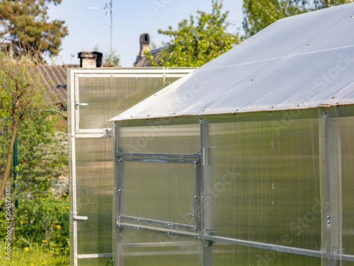 Modern polycarbonate greenhouse structure with clear panels and metal frame in a garden