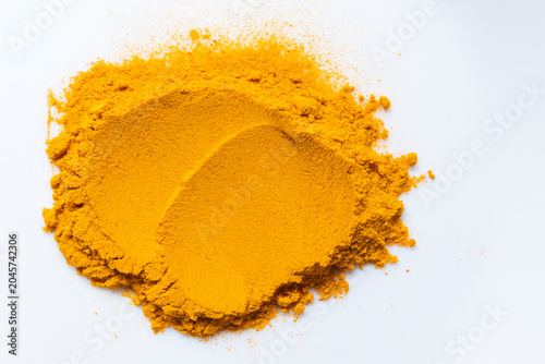 Top view of bright yellow turmeric powder smear isolated on white background. Abstract textured streak of orange curcuma powder flat lay on white canvas. Golden turmeric powder splash texture close up
