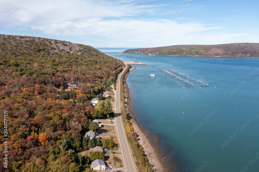 Obraz premium Aerial drone view of coastal road autumn woodland and salmon farming pens near Digby Nova Scotia Canada on the Bay of Fundy in the autumn time