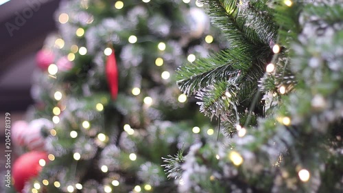 red and white striped christmas ball hanging on green pine branch with glowing warm lights around. festive holiday macro shot