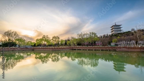Sunset over tranquil lake with pagoda and tree reflections