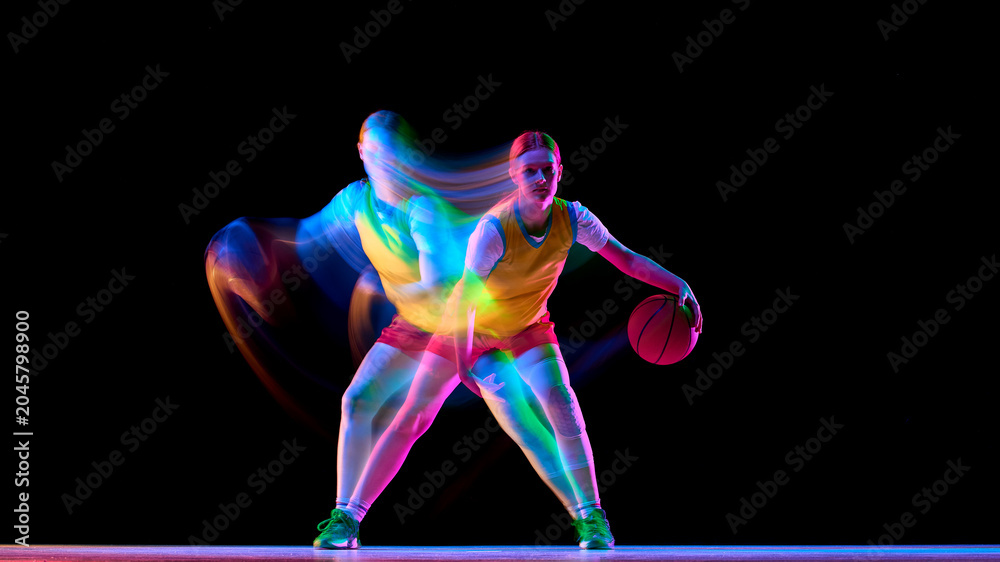 Naklejka premium Focused basketball player in defensive stance with neon motion blur. Concept of defensive training, agility coaching, sport psychology, and modern basketball advertising.