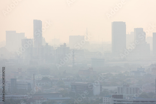 Silhouettes of tall modern city skyscrapers covered in thick toxic smog and heavy air pollution.