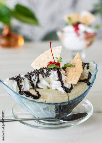 banana split ice cream sundae dessert on white table in outdoor garden cafe