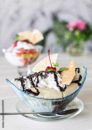 banana split ice cream sundae dessert on white table in outdoor garden cafe