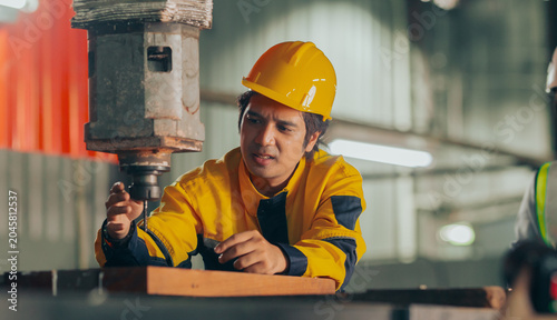 Photography Group of diverse Asian technicians and female industry specialists collaborating next to production machinery, checking maintenance checklists and auditing plant operations to ensure workplace safety