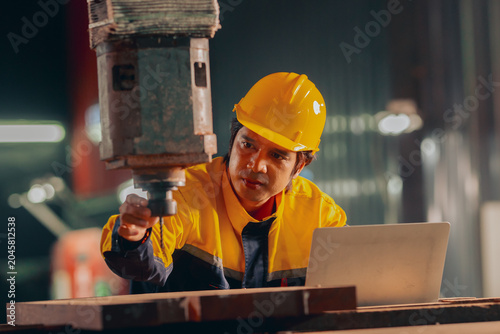 Canvas Print Group of diverse Asian technicians and female industry specialists collaborating next to production machinery, checking maintenance checklists and auditing plant operations to ensure workplace safety