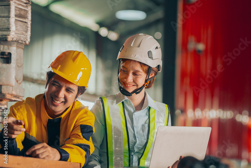 Schilderij op canvas Group of diverse Asian technicians and female industry specialists collaborating next to production machinery, checking maintenance checklists and auditing plant operations to ensure workplace safety
