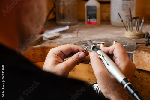 Foto Primer plano de las manos de un hombre joyero lijando una pieza en su taller