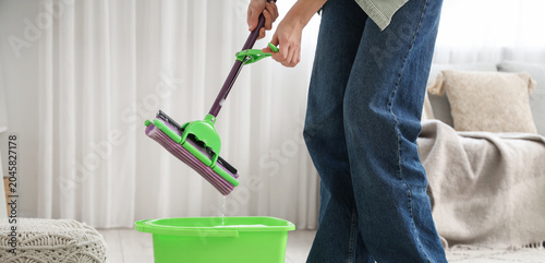 Photos Woman wringing out mop with bucket in room