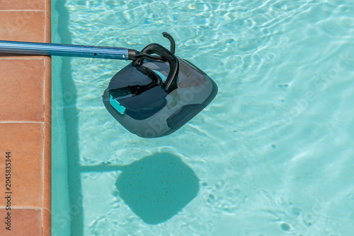 A cordless pool cleaner robot is retrieved with a special hook attached to a telescopic pole