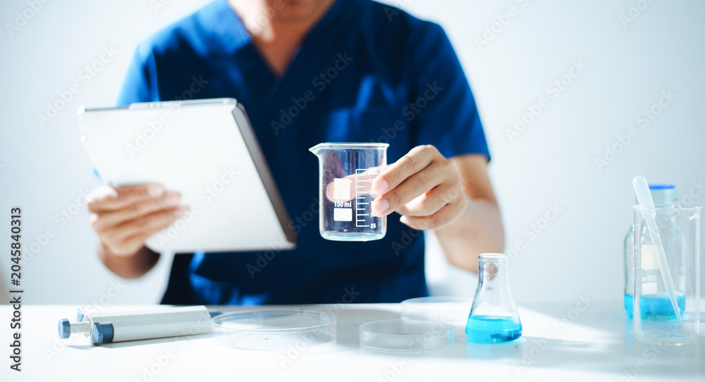 Fototapeta premium A professional scientist in a lab coat inspecting blue and white medical capsules on a petri dish. Concept of pharmaceutical research, health care development