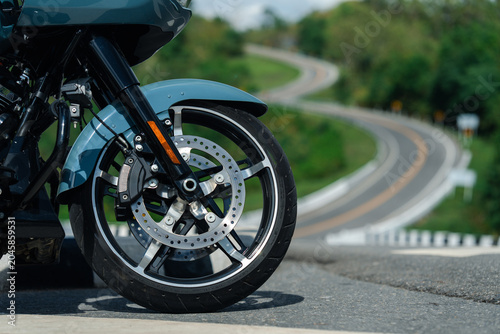 Close up of motorcycle front wheel with disc brakes on scenic winding road