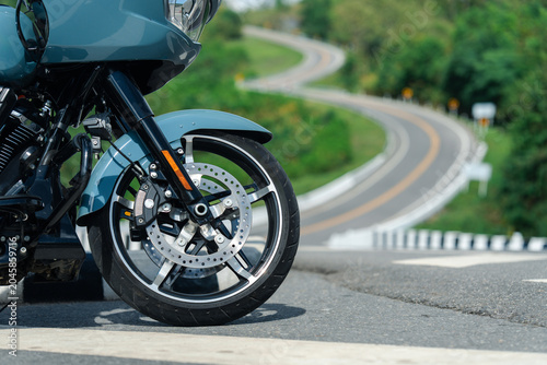 Sleek motorcycle parked on scenic winding road, showcasing its front wheel and disc brake detail