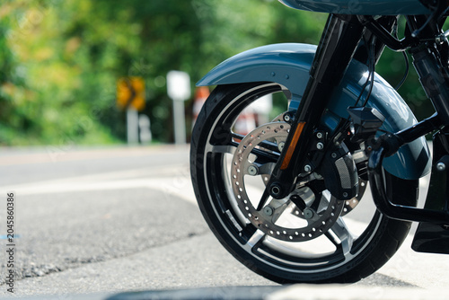 Close up of blue motorcycle front wheel with disc brakes on sunny day