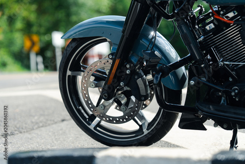 Close up of motorcycle front wheel with shiny disc brake and sleek tire on sunny day