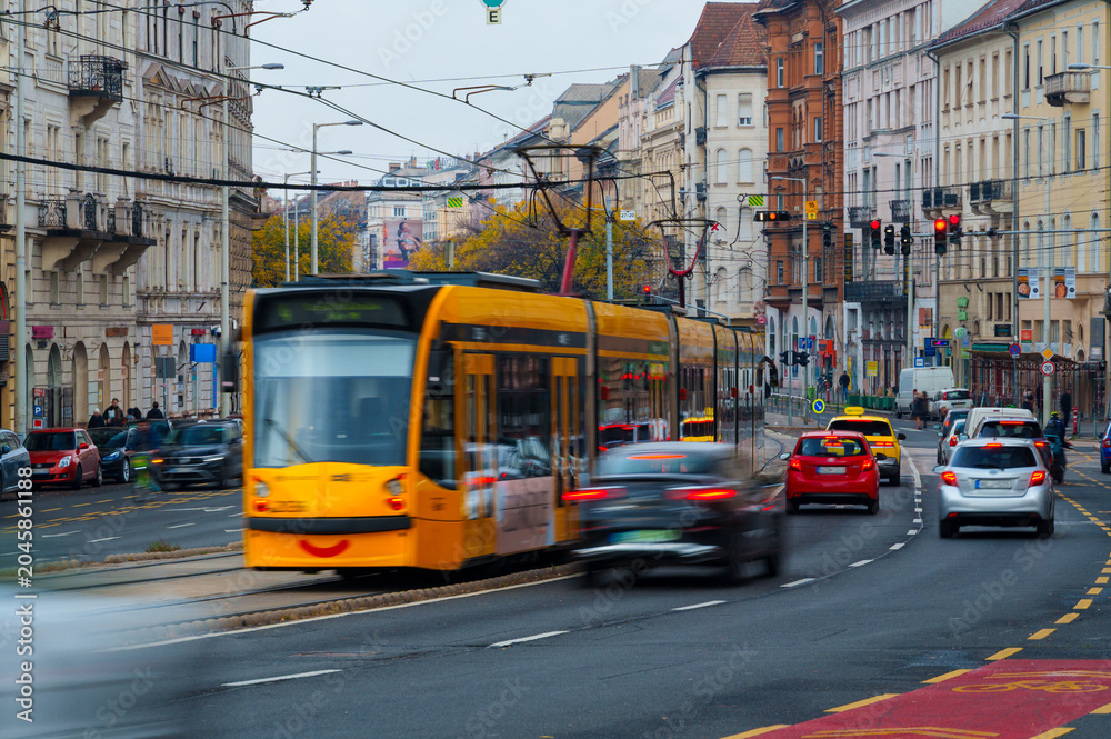 Fototapeta premium Yellow tram in motion on the streets of Budapest with cars and historic architecture