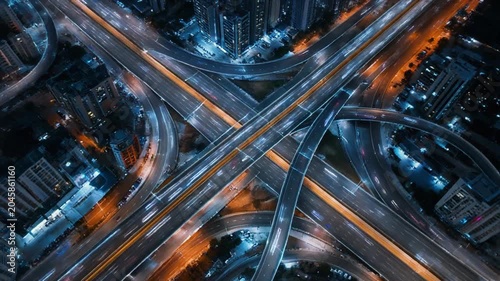 Aerial highway interchange at night with glowing car light trails capturing vibrant urban motion video footage