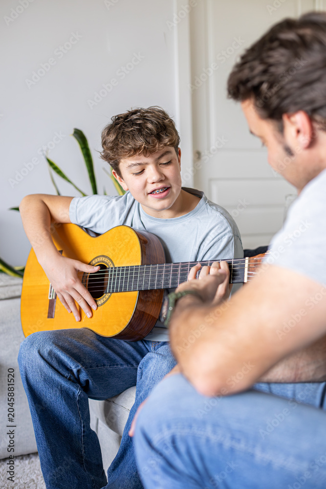 Fototapeta premium Father teaching son playing acoustic guitar at home