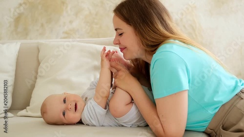 mother and baby, mother gently kissing the baby, playing with its legs, mother's love and care