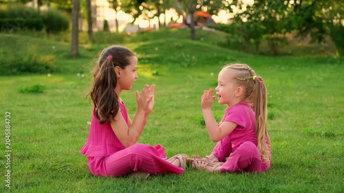 children in the park in summer, little girls walking and having fun on a green lawn, playing, summer holidays