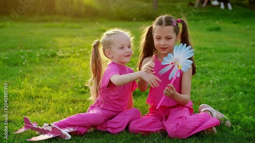 children in the park in summer, little girls walking and having fun on a green lawn, playing, summer holidays