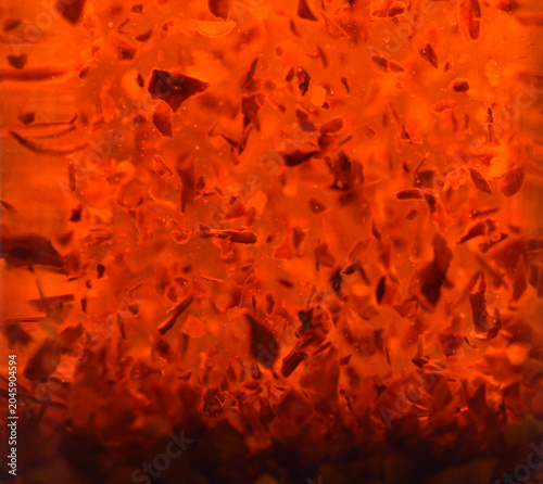 Fotografia Fiery hot chilli pepper flakes suspended floating in red olive oil