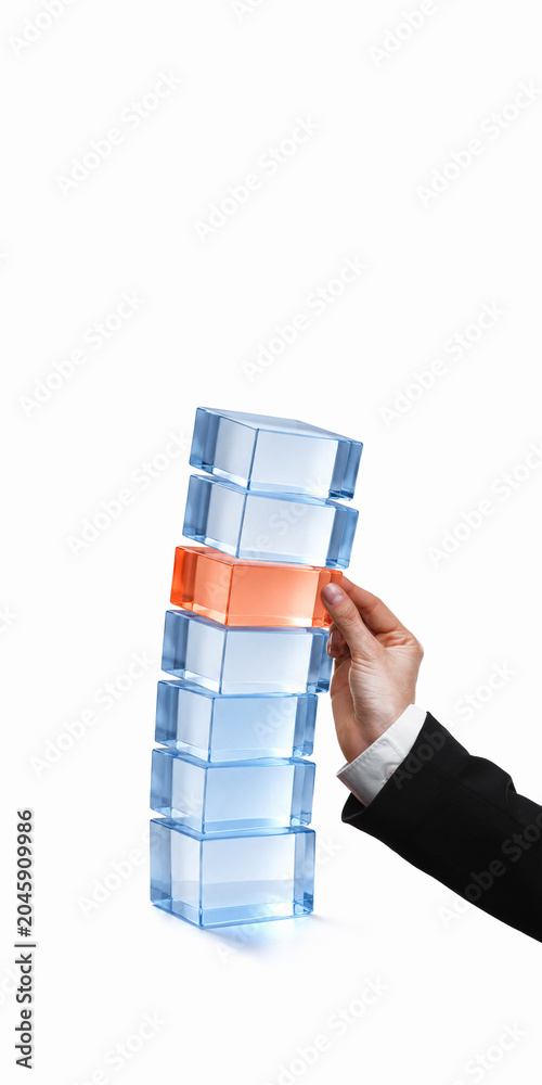 Naklejka premium Hand inserting orange 3d block into unstable glass tower. Concept of crisis management, audit control, insurance risk, compliance gaps and business protection.