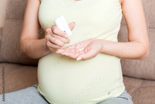Canvastavla Midsection of pregnant woman taking vitamin pill on sofa at home