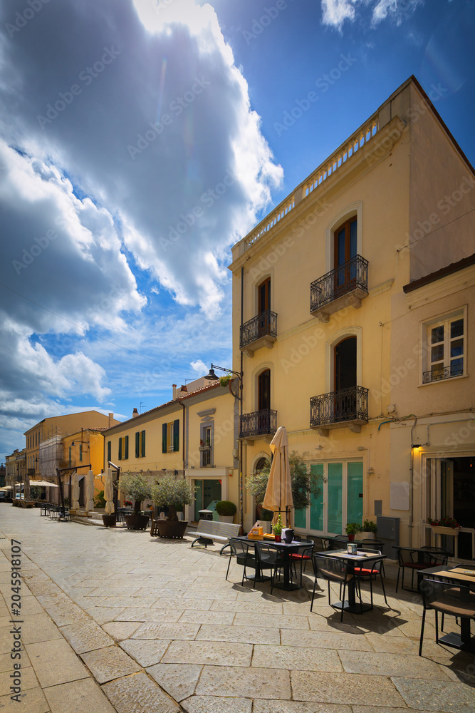 Obraz premium Narrow cobblestone street with colorful buildings in Olbia, Sardinia, Italy - background or travel wallpaper