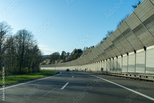 Curving highway with noise barrier in spring landscape